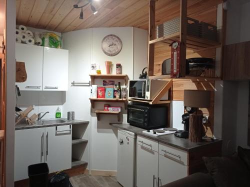 a small kitchen with white cabinets and a microwave at Résidence le Schuss Studio Montagne en bas des pistes in Vars