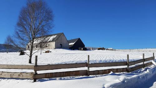 a barn in a snow covered field with a fence at Wzgórze Owiec Sheep Hill in Mostowice