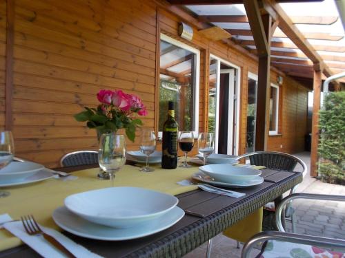 Fonyód Camping & Apartman في فونيود: طاولة مع صحون و كاسات و إناء من الزهور