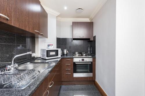 a kitchen with a sink and a microwave at Sanctum Maida Vale in London