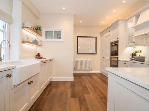 a kitchen with white cabinets and a hardwood floor at The Middle House in Southwold