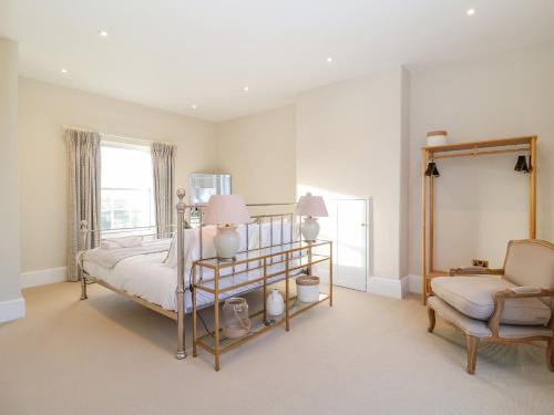 a bedroom with a bed and a chair and a window at The Middle House in Southwold