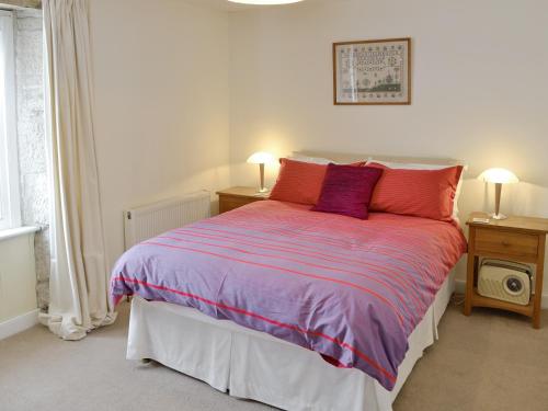 Lime Cottage في بورتلاند: غرفة نوم مع سرير مع الوسائد الأرجوانية والحمراء