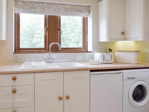 een keuken met een wastafel en een wasmachine bij Woodpecker Cottage - Ukc3412 in Bolton by Bowland