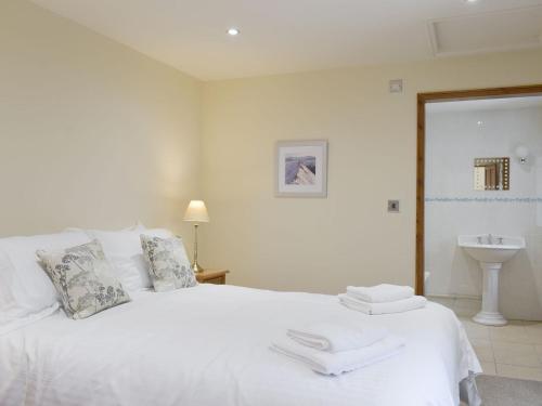 een slaapkamer met een wit bed en een wastafel bij Woodpecker Cottage - Ukc3412 in Bolton by Bowland