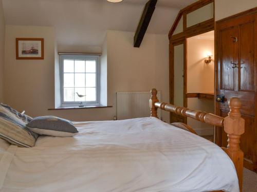 a bedroom with a large white bed with a window at Bryn Golau in Llanfaethlu