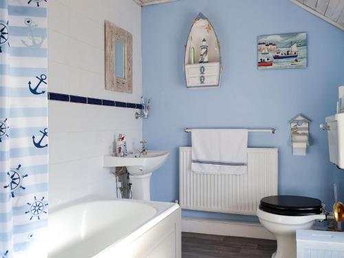 a bathroom with a tub and a toilet and a sink at Bryn Golau in Llanfaethlu