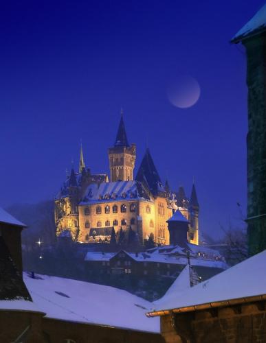 a large castle in the snow at night at Landhaus Tonmühle in Ilsenburg