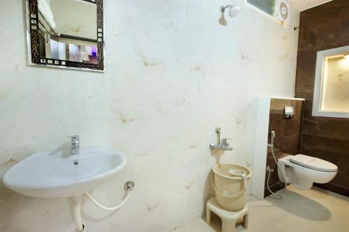 a bathroom with a sink and a toilet and a mirror at Mannars Deluxe Lodge in Mysore