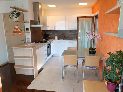 - une cuisine avec des placards blancs, une table et des chaises dans l'établissement Patty ZU - Lakeside apartment, à Riva di Solto