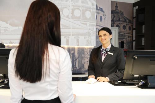 a woman in a suit standing at a desk at Mercure Bucharest City Center in Bucharest