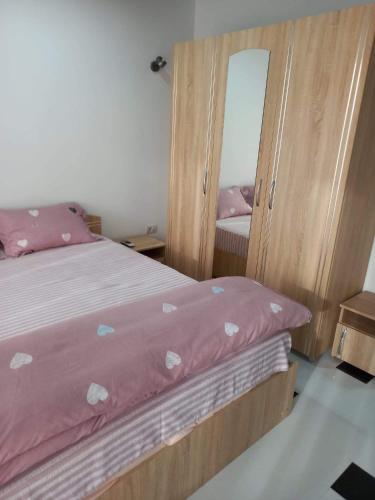 a bedroom with a bed with pink sheets and a mirror at Apartament 2 dormitoare și living bloc nou in Năvodari