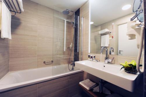 a bathroom with a tub and a sink and a bath tub at Mercure Bucharest City Center in Bucharest