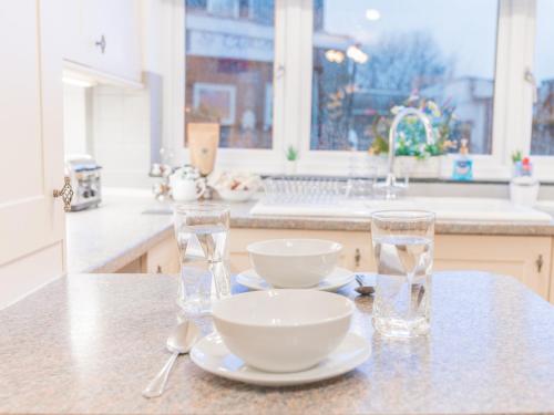 a kitchen counter with two glasses and bowls on a table at Lakeland View in Keswick