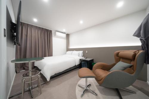 a hotel room with a bed and a table and chairs at Jawoori Hotel Incheon Songdo in Incheon
