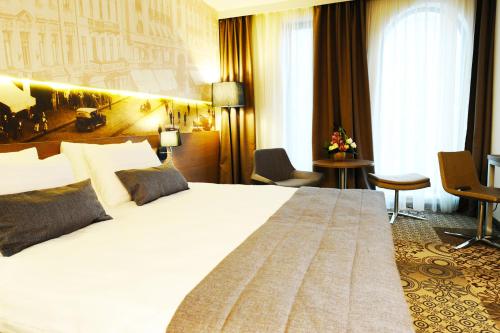 a hotel room with a large white bed and chairs at Mercure Bucharest City Center in Bucharest