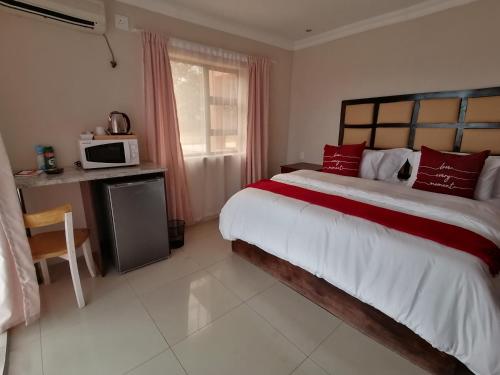 a bedroom with a large bed and a microwave at Rondy Bosch Lodge in Louis Trichardt