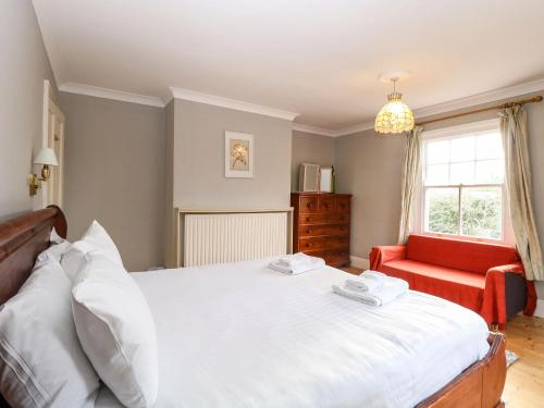 a bedroom with a large bed and a red chair at Croylands in North Walsham