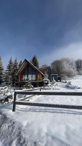 una cabaña de madera en la nieve con una valla en Chalet Donky, en Donovaly