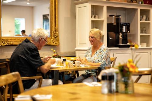 a man and woman sitting at a table in a restaurant at Hotel Restaurant Eeserhof in Ees