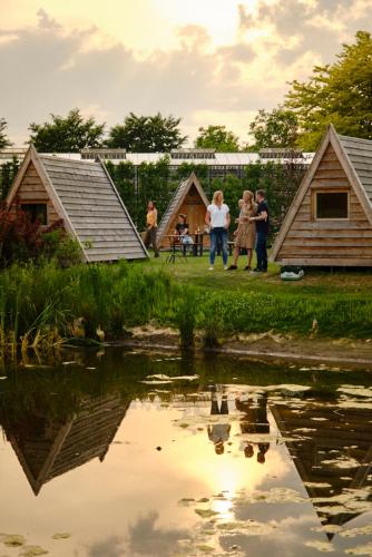 a group of people standing around a pond with playhouses at Achterhoeks Goed, Minicamping in Vragender in Vragender