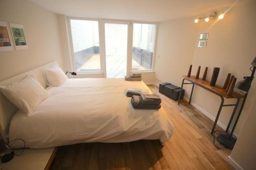 a bedroom with a large white bed and a window at Charmant appart 2 ch avec terrasse en centre ville in Liège