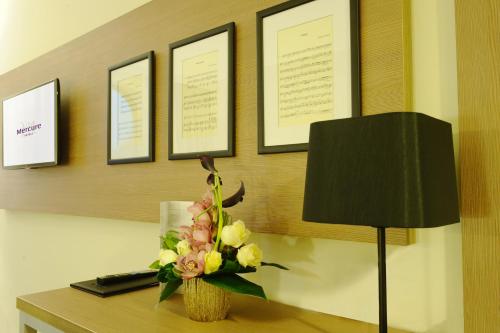 a vase of flowers on a desk with a lamp at Mercure Bucharest City Center in Bucharest
