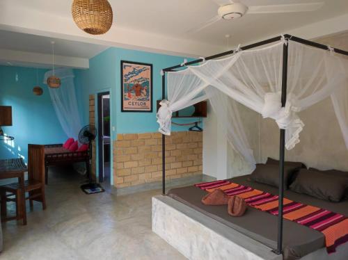 a bedroom with a canopy bed and a living room at EKUKU lake houses in Kumbalgama