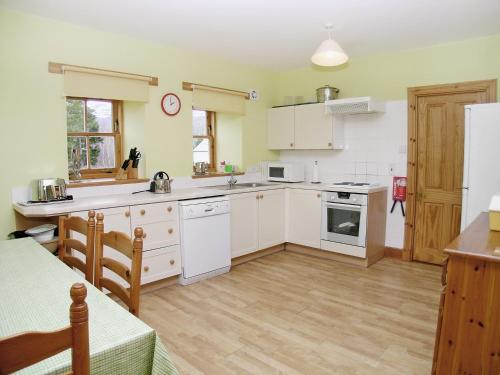 a kitchen with white cabinets and a counter top at Mar House in Braemar