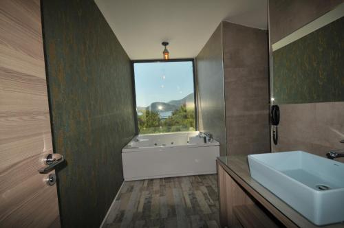 ein Bad mit einer Badewanne, einem Waschbecken und einem Fenster in der Unterkunft Class Unique Beach in Marmaris