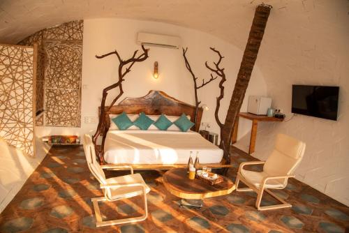 a bedroom with a bed and two chairs and a table at Obrigado by Craftels in Cabo de Rama