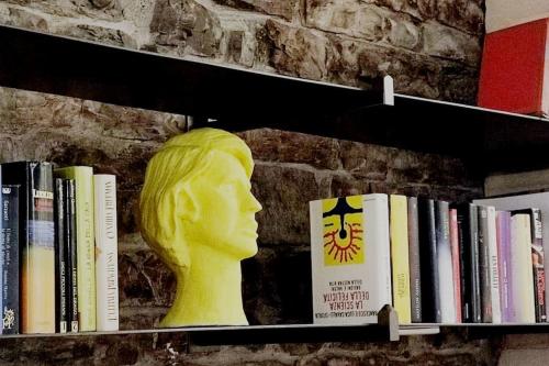 a book shelf with books and a head on it at Appartamento Torre della Buca in Prato