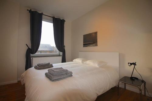 - une chambre avec un lit blanc et des serviettes dans l'établissement Duplex de 3 chambres en plein centre ville - 82/3A, à Liège