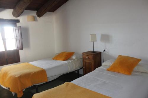 a bedroom with two beds with orange sheets and a window at La Siesta VTAR in El Alcornocal