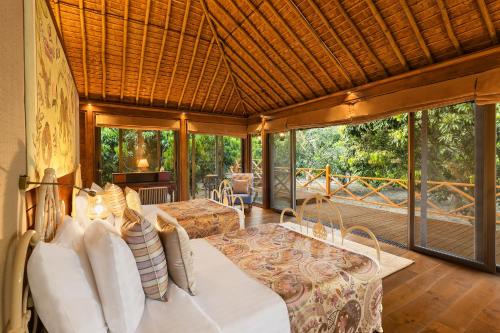 a bedroom with a bed in a room with a deck at Jaagir Manor, Dudhwa - IHCL SeleQtions in Paliā Kalān