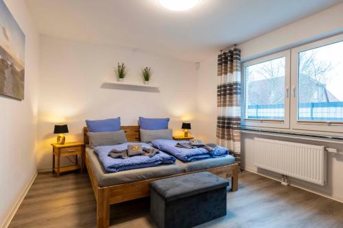 a bedroom with a bed with blue sheets and a window at Küsters Ferienhaus Tinchen in Norden