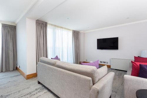 a living room with a couch and a tv at Sanctum Maida Vale in London