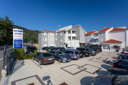 un montón de autos estacionados en un estacionamiento en Apartments Crnekovic Tomislava 8A, en Baška