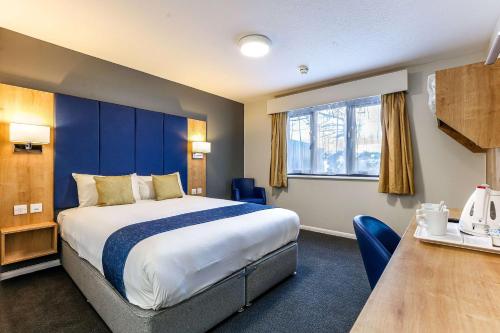 una camera d'albergo con un grande letto e un tavolo di Days Inn London Stansted Airport a Stansted Mountfitchet