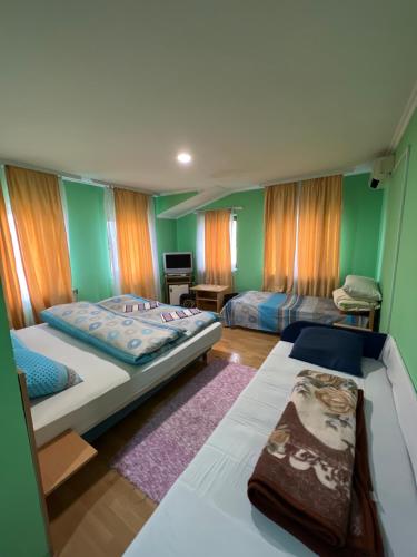 two beds in a room with green walls at Ribarska Priča-Restoran pansion Prijedor in Prijedor