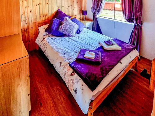 a bedroom with a bed with purple sheets and a window at Wildwood 5 in Beattock