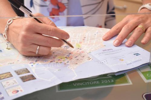 a woman holding a pen and pointing at a map at Actinia Accommodation in Alghero