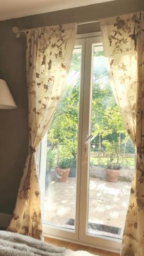 d'une fenêtre avec des rideaux et une vue sur un patio. dans l'établissement Petite chambre coquette, à Cellettes