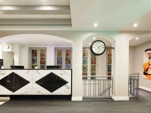 um átrio com um relógio na parede e uma recepção em ibis Styles Amsterdam Central Station em Amesterdão