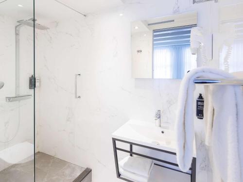 a white bathroom with a shower and a sink at ibis Styles Amsterdam Central Station in Amsterdam