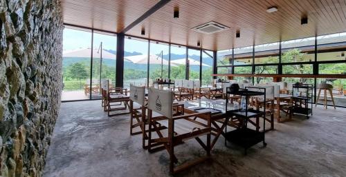 un comedor con mesas, sillas y ventanas en La Levée Resort, en Sai Yok