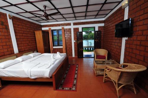 a bedroom with a bed and a tv in a room at The Lake by Maat Hotels in Alleppey