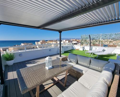 un patio con sofá y una mesa en el techo en Ático Los Flamingos. Exclusive terrace with views, en Cabo de Gata