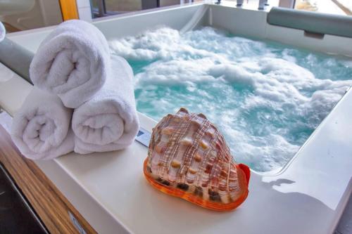 a bath tub with towels and a shell on a table at Suite Villa Aquamarina con Jacuzzi Riservata in Porto Pino