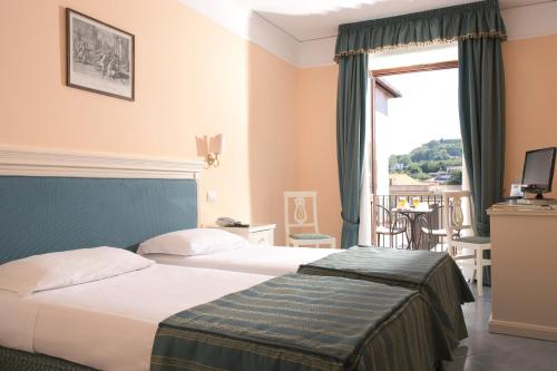 a hotel room with two beds and a window at Hotel Jaccarino in SantʼAgata sui Due Golfi
